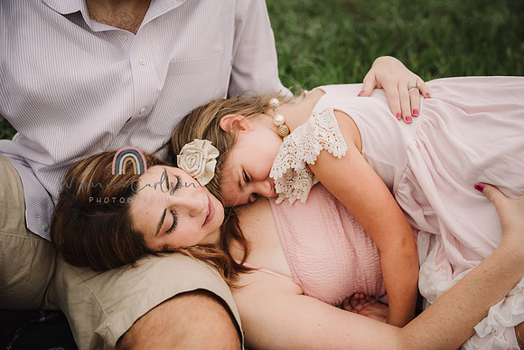 mother lays down on the ground and daughter lays on her chest