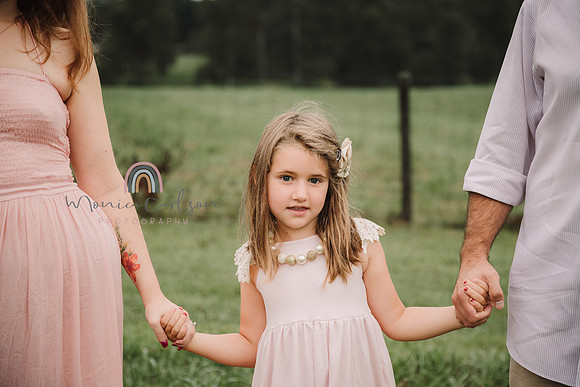 little girl dressed in pink holds parents hands at Prospect farms