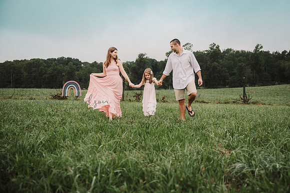 family of three walks through a open field on a farm in lawernceville, ga on a sunny day