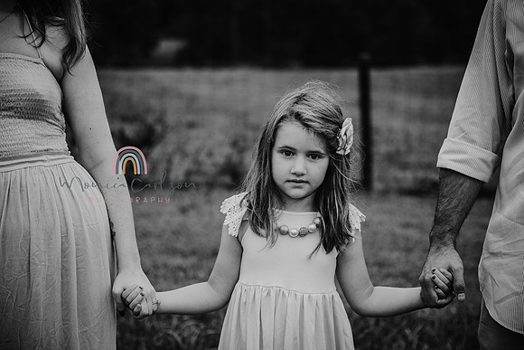black and white image of a little girl holding her parents hands