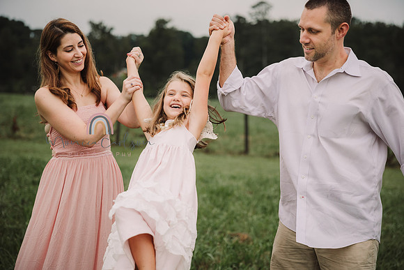 mother and father swing their daughter by her arms