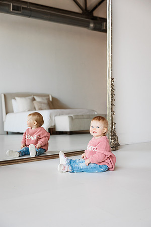 little girl sitting in front of huge mirror