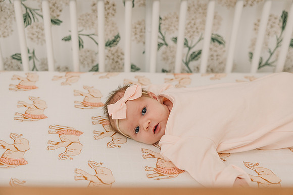 portrait of a baby girl laying in her crib