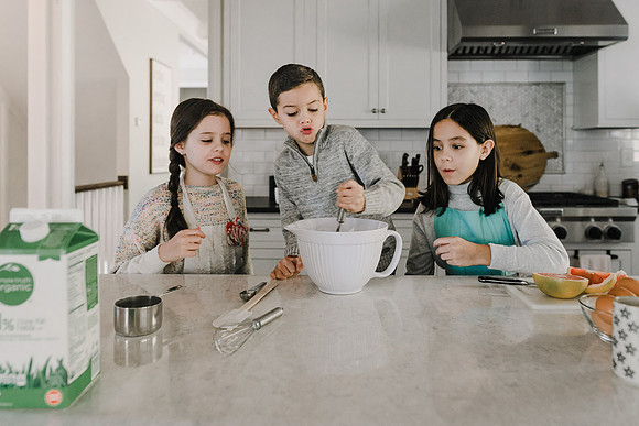 three siblings cooking during a home photo session by monica carlson