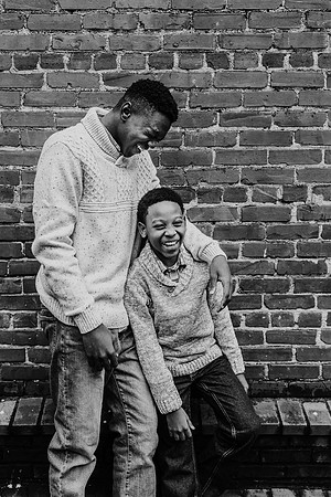 african american brothers laughing in front of a brick wall