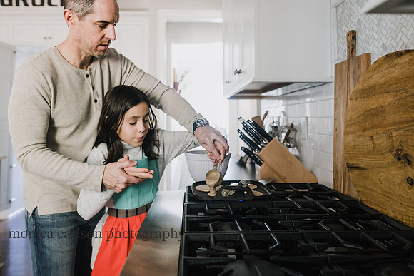 father helping his daughter flip a pancake