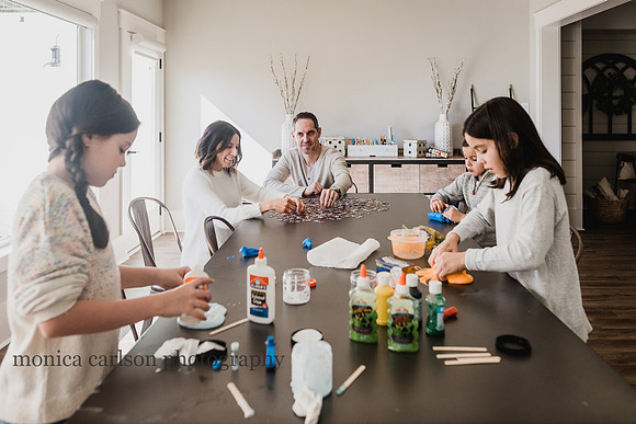 family of five sitting at a table making slime and puzzles by monica carlson photography