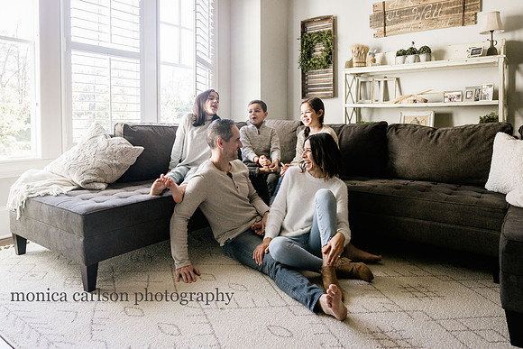 family relaxing in their living room during a photo session with monica carlson