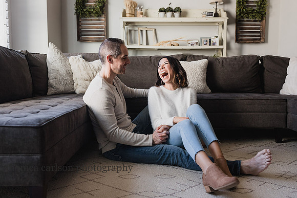husband and wife laughing together in their living room while sitting on the floor