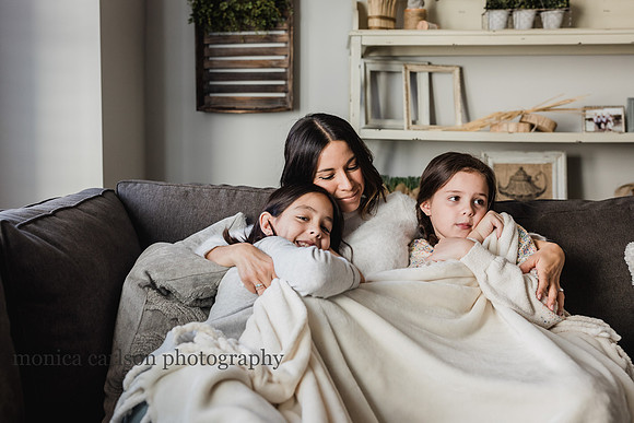 mother cuddling her son and daughter on the couch of their living room