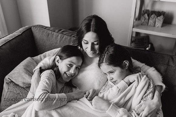 black and white portrait of a mother with her son and daughter snuggled on the couch at home by monica carlson photography