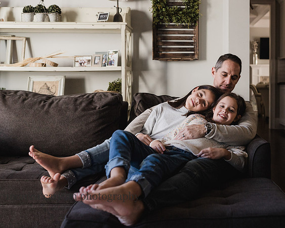 father snuggling his tween daughter on a couch