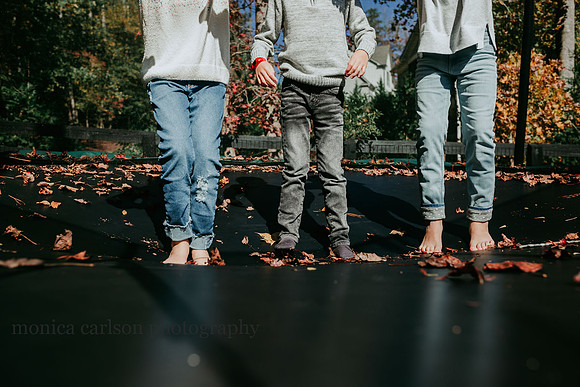 waist down photo of three kids standing on a trampoline