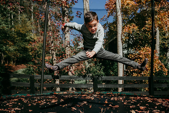 boy doing a straddle jump on a back yard trampoline