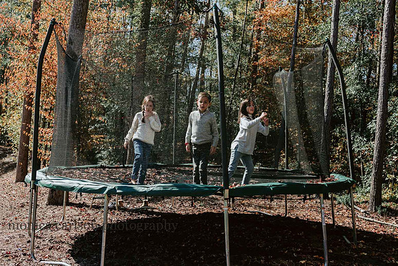 three kids jumping on a home trampoline