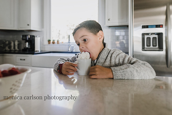 little boy eating whipped cream off his hot cocoa by monica carlson photography