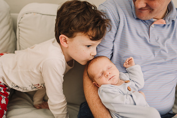 Young boy kisses baby brother on the head