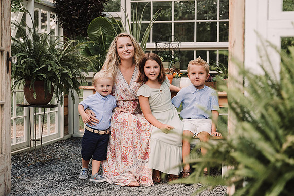 Portrait of a mom with her three kids in a greenhouse by monica carlson photography