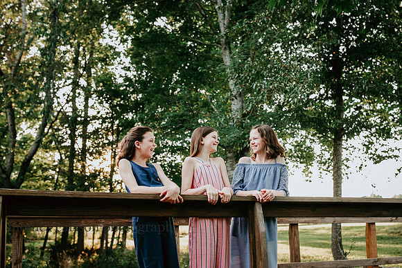 sisters laughing together on a bridge