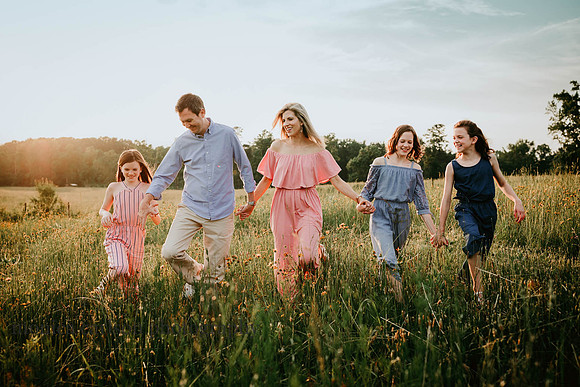 beautiful family walking in a field of flowers during a photo session
