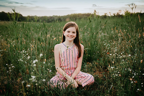 tween girl sitting in a wild flower field by Monica carlson