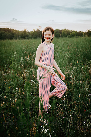 smiling young lady walking through a flower field during a family photo session