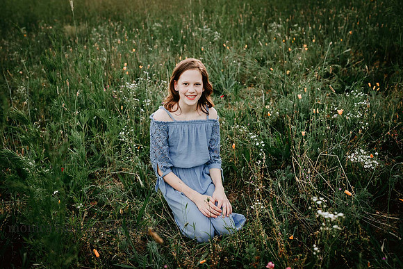 brown hair tween sitting in a flower field