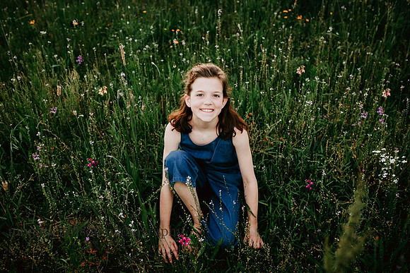 young girl sitting a field of flowers