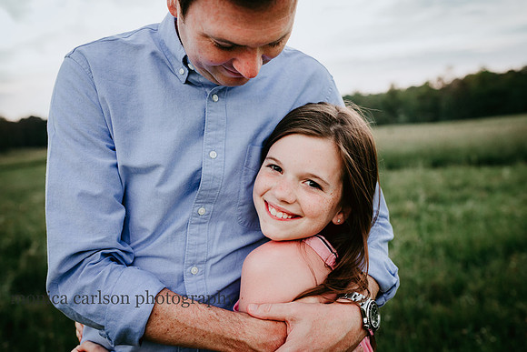 father hugging his young daughter on a open field