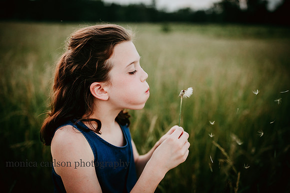 girl making wishes with a dandelion during a family photo session