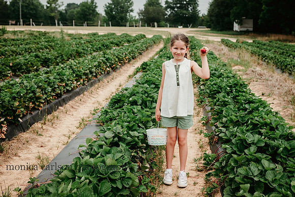 girl happily showing off a strawberry she just picked