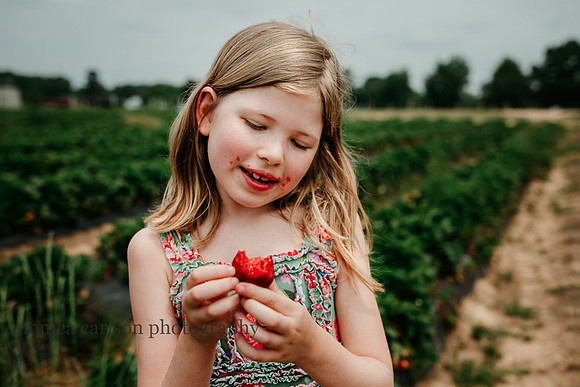 girl with stained cheeks enjoying her fresh strawberries