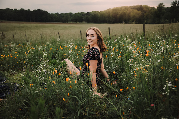 Teen sitting in a field of flowers at sunset