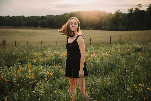high school senior flipping her hair on a wildflower field