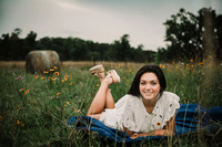high school senior laying on a blanket in a wildflower field