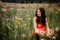 Happy 14 year old girl sitting in a bright field of flowers