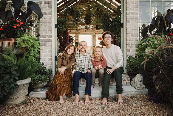 Four siblings sit together at green house door