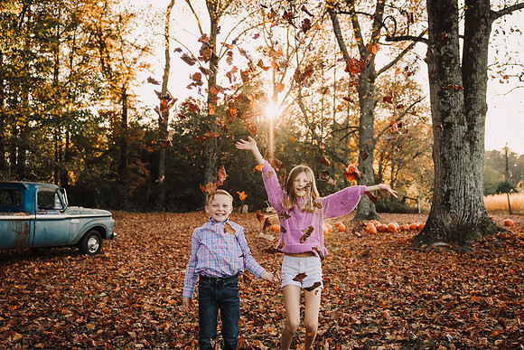 Brother and sister throw leaves in the air joyfully