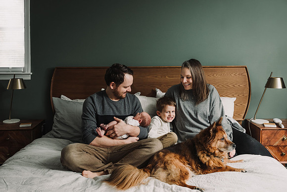 Family sits on a bed with their dog