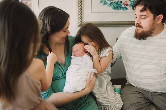 Sister lovingly snuggles baby brother