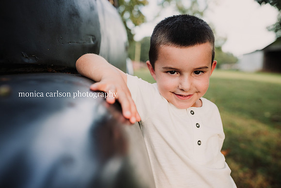portrait of a boy leaning against a pick up truck
