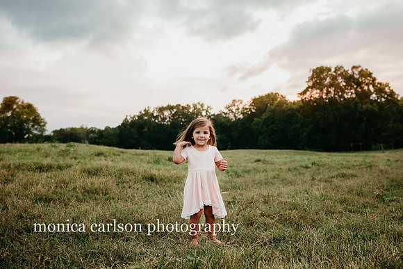 sweet little girl in a pink dress at sunset at milford family farm