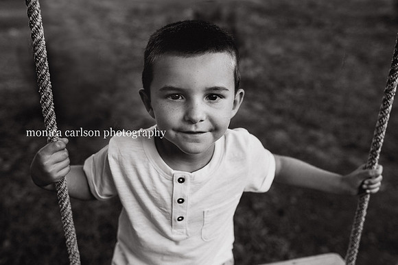 black and white portrait of a boy on a tree swing