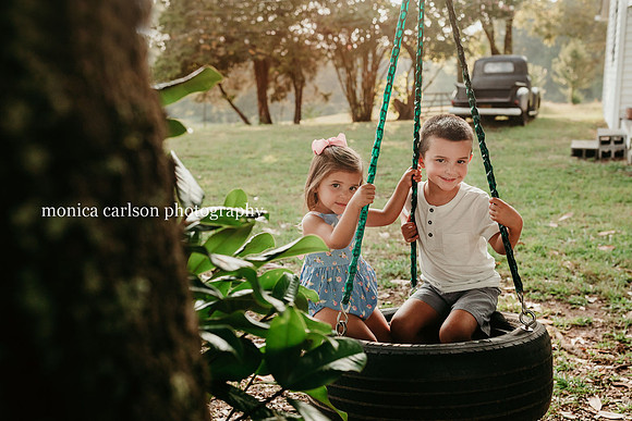 brother and sister sitting on a tire swing at milford family farm in cumming