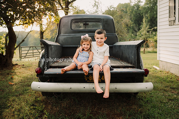 adorable siblings sitting on a old truck during a photo session with monica carlson photography