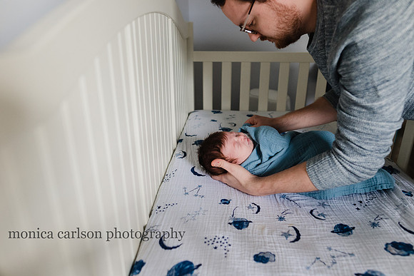 father laying his swaddled son in his crib in atlanta, GA
