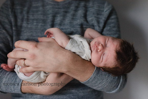 Sweet newborn baby sleeping in his father arms during a family photography sessionion