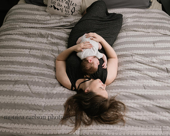 mother laying on a bed with her newborn baby