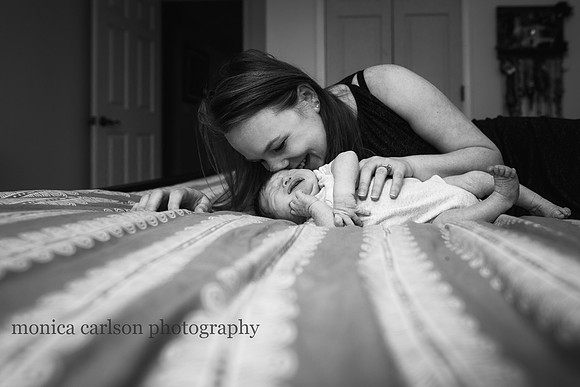 mother snuggles a crying baby on her bed