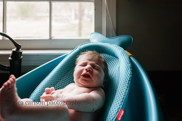 baby boy in a bath by a window in his home